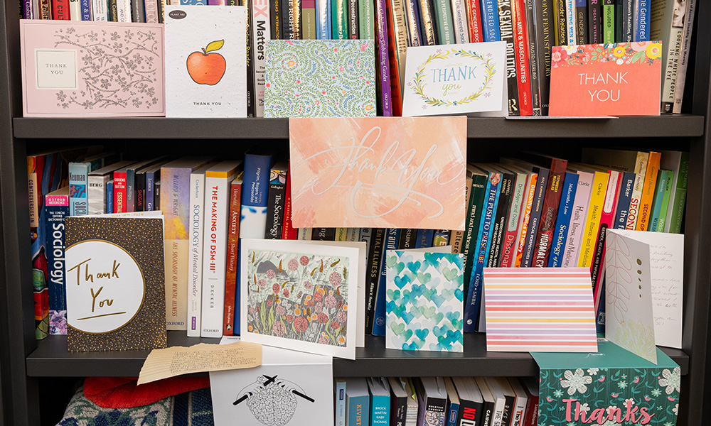 A bookshelf filled with sociology books and thank you cards