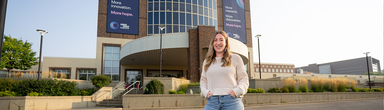 kelsey swank stands in front of the circular-shaped entrance to the Cross Cancer Centre