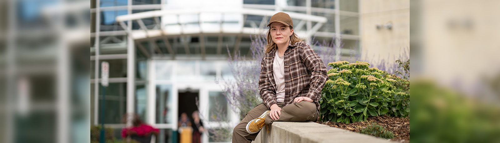 Syd Wells sits on a concrete flower planter outside of the clock tower entrance at MacEwan.