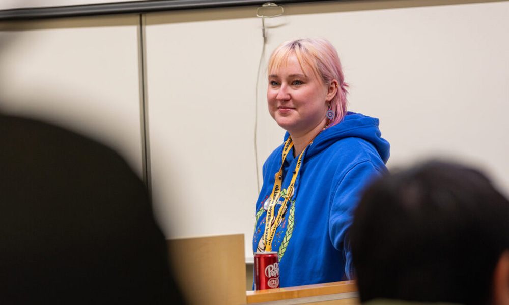 A woman in a blue hoodie stands and watches the Life Kits being assembled.