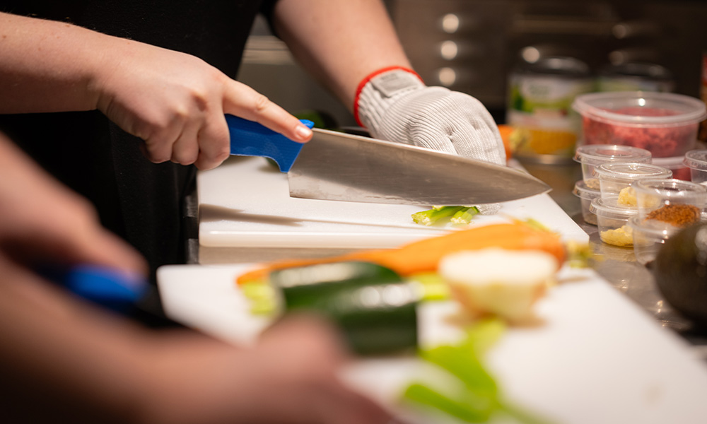 A close-up of a knife dicing assorted vegetables.