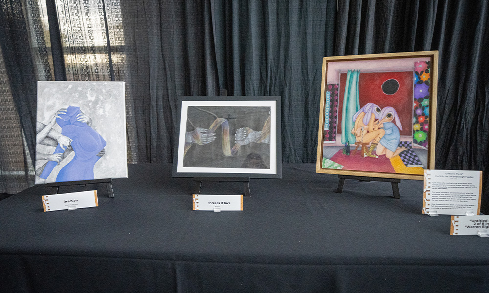Three paintings sit on a table together.