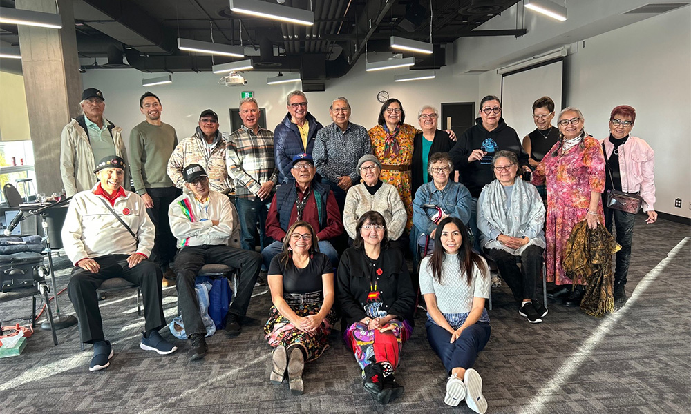 A large group of people pose together in a conference room in Allard Hall.