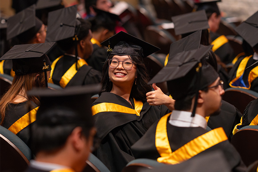 A graduate giving a thumbs-up