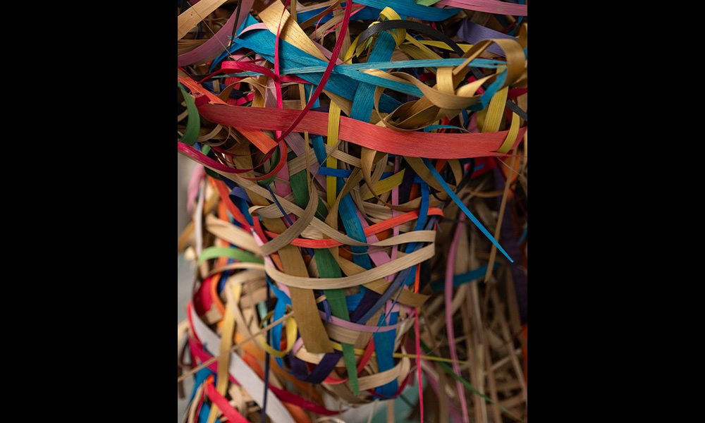 A close-up of colourful strips of wood intertwined and woven together.