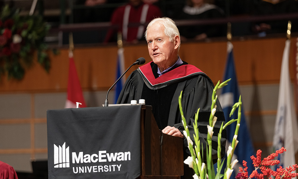 Dr. Kolb addresses grads from the lectern on stage at the Winspear