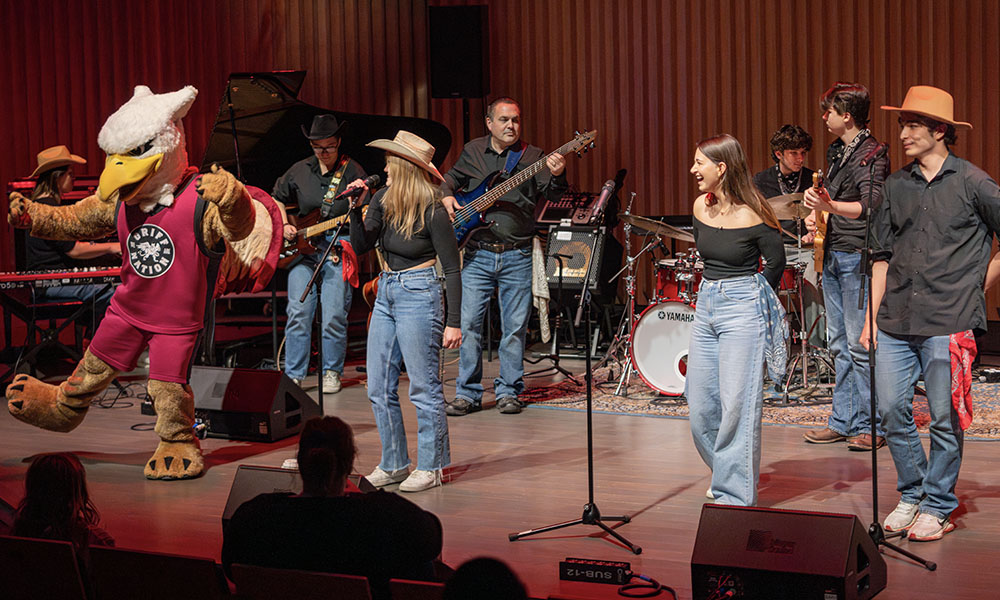 MacEwan's mascot, Griff, dances on stage with musicians