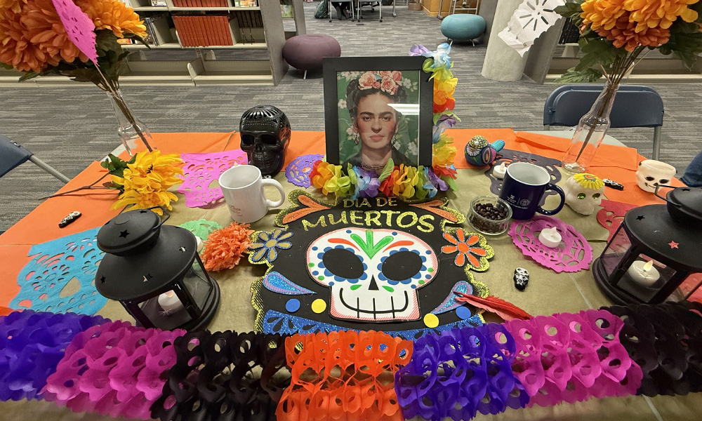 A colourful alter for Dia de los Muertos with streamers, drawings and a photo