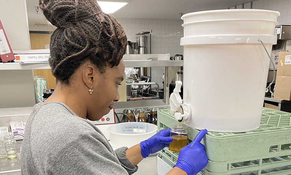 A volunteer decants honey into a glass jar