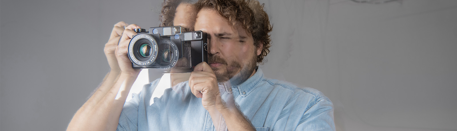 An intentionally blurred photo of Colin Wagh looking through the viewfinder of a large-format camera