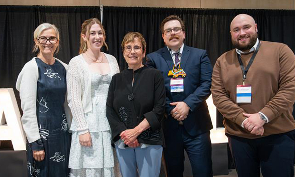Five people stand on a stage 