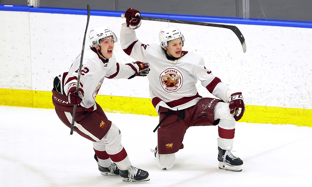 Two men hockey players cheer and hold their sticks in the air. 