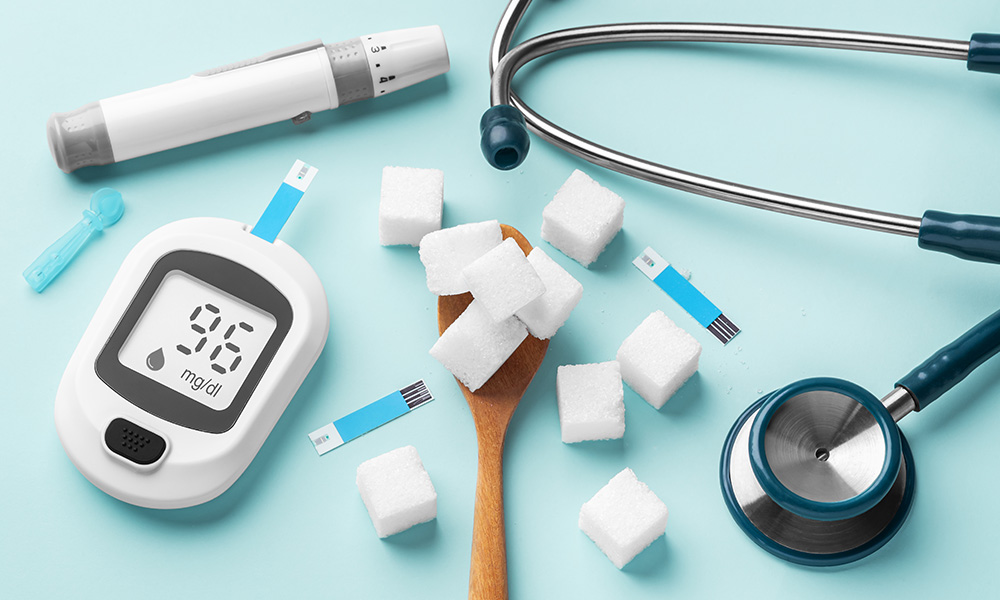Sugar cubes in spoon with blood glucose meter, lancet and stethoscope on blue background