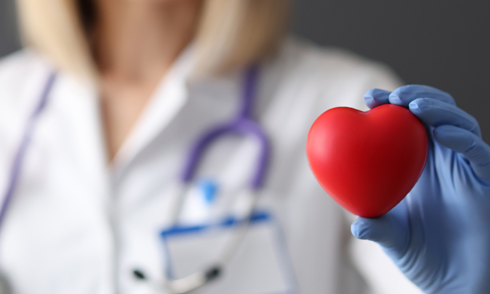 TitleDoctor in rubber gloves holding red toy heart 