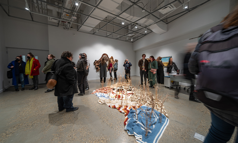 Observers look at an art display dealing with agriculture in the Mitchell Art Gallery.