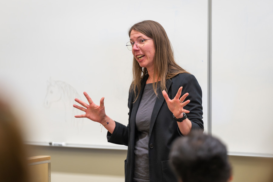 A woman hold her hands out while speaking to a room of conference attendees