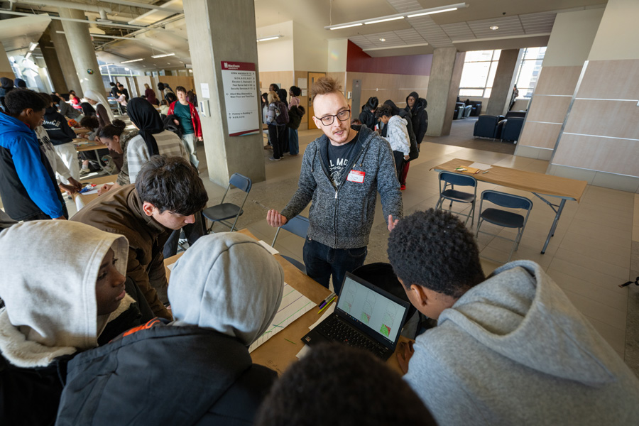 A MacEwan student stands in front of a group of junior high students