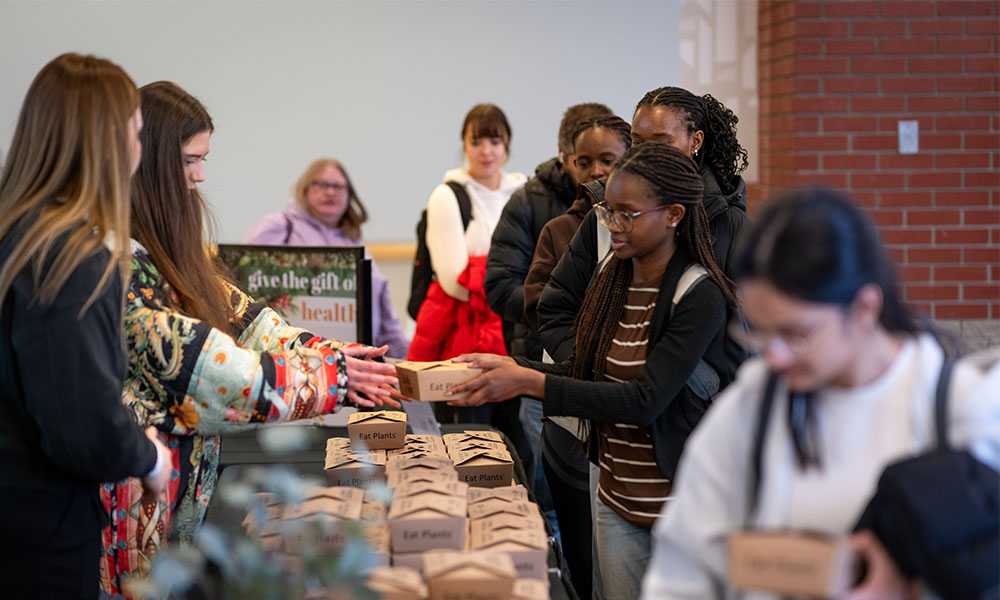 people handing out boxes of food to students