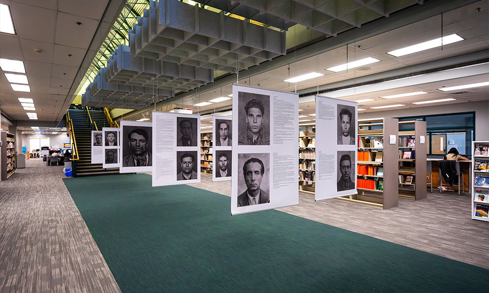 An exhibition displaying large posters of men's faces with letters printed out beside them