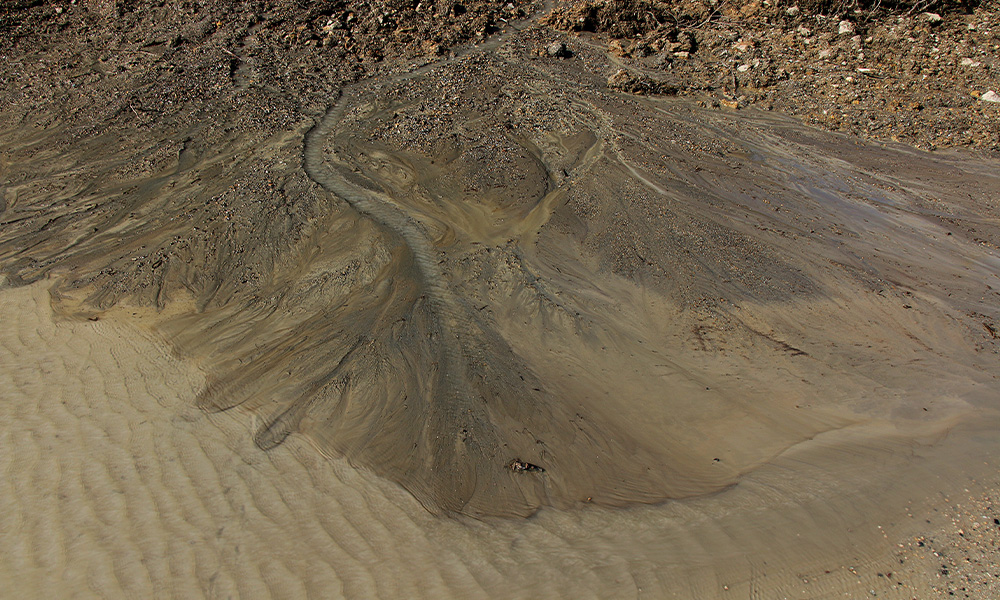 Oil sands tailings run through dirt.