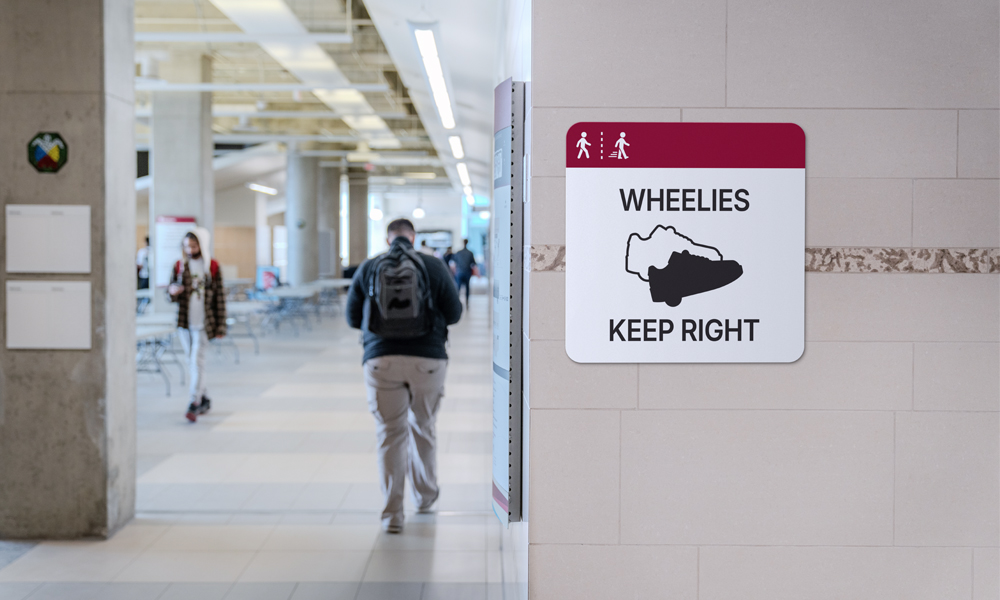 A hallway in Building 9 is seen with a sign on the wall denoting that wheelie users must stay to one side of the corridor.