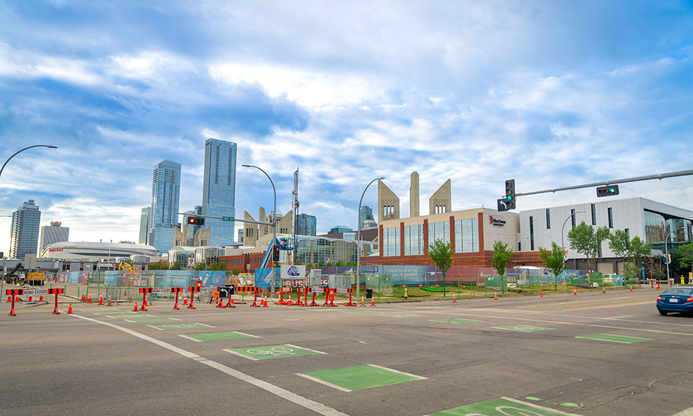 The view across the street from an empty plot of land surrounded by construction fencing and pylons
