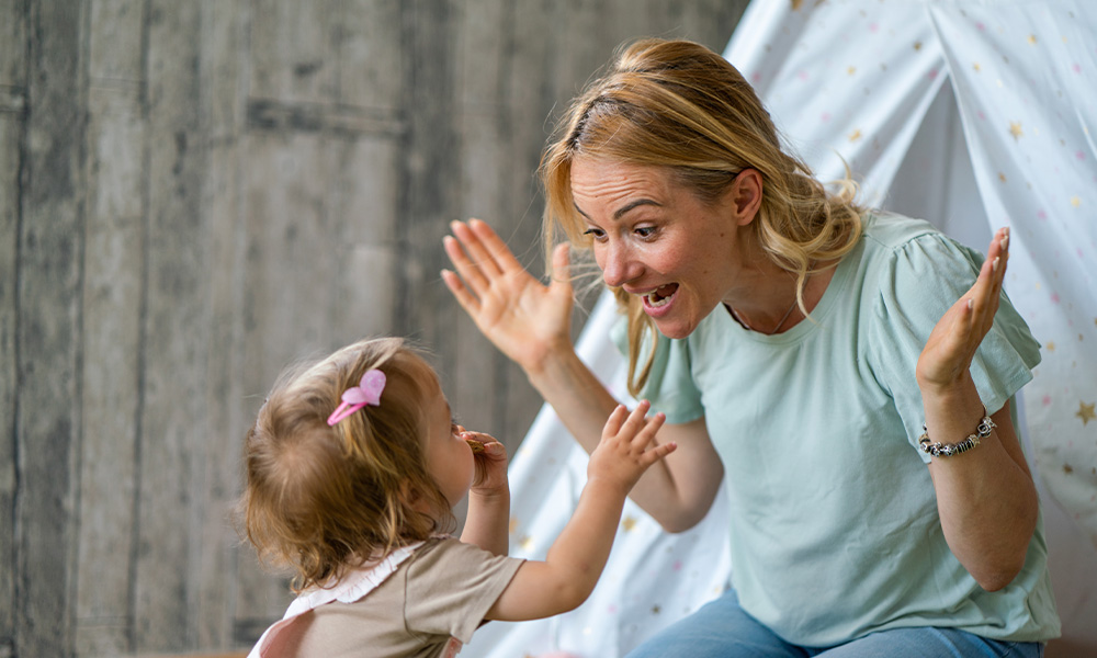 A parent looks at a toddler with an expressive face.