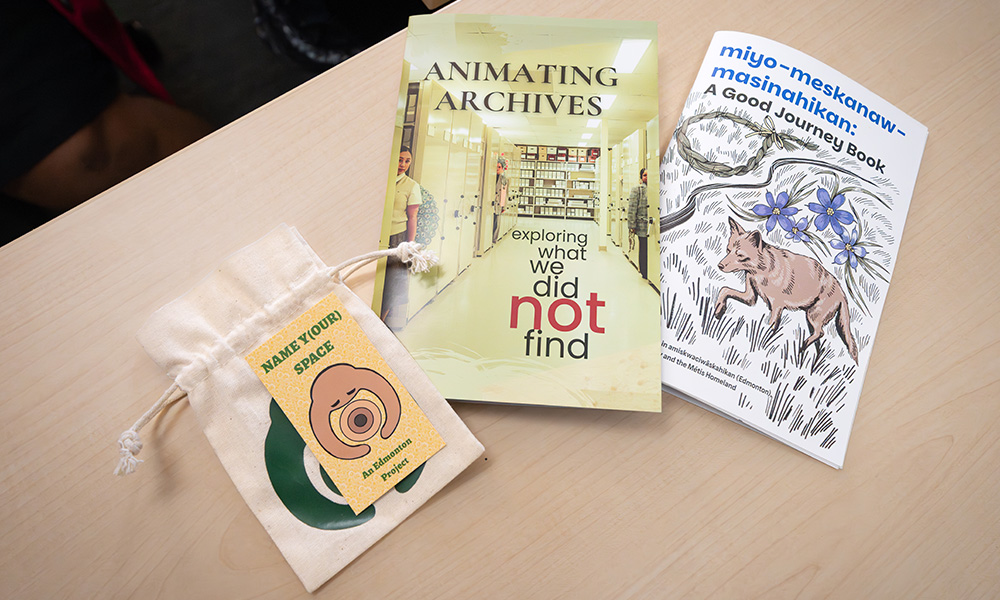 Three pieces of research are laid side by side, one having an info card and small canvas bag, and the other two being pamphlets.