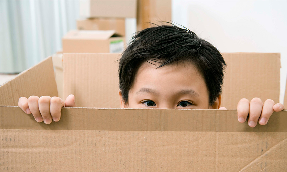 A child peeks over the edge of a cardboard box