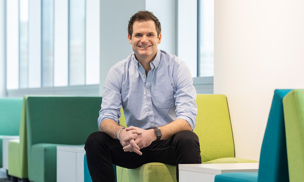 Steve Jodoin sits on a green chair in Allard Hall