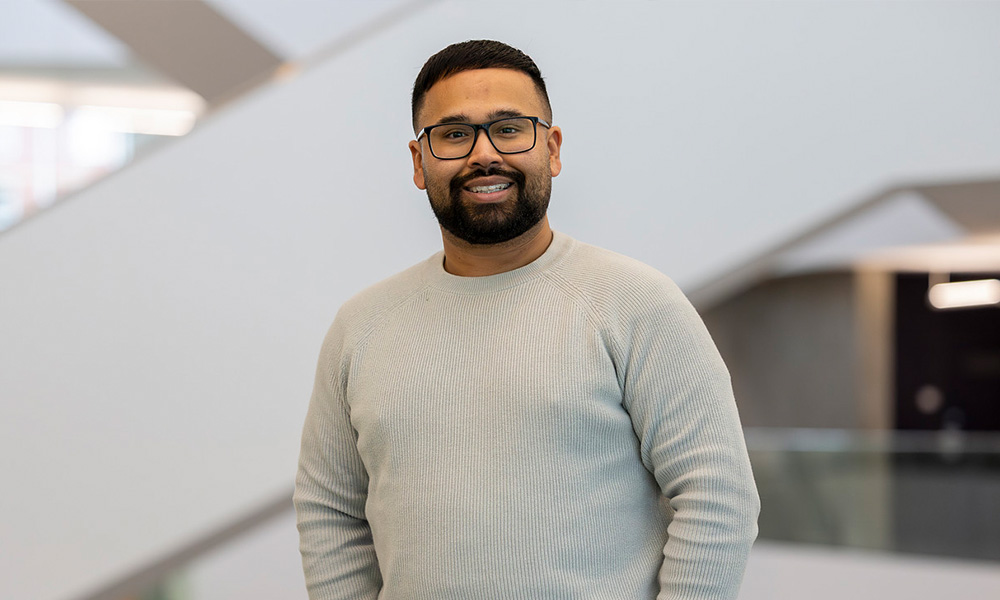 Sunny Johal stands in front of a staircase in Allard Hall
