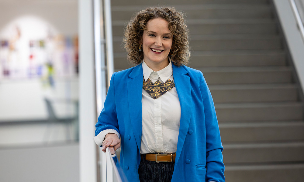 Sheena Rossiter stands in front of a staircase in Allard Hall