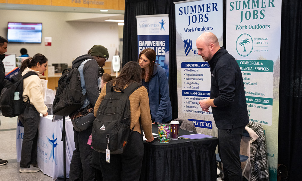 Students speak with reps at a job fair booth.