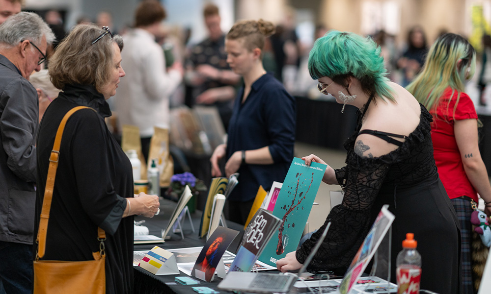 A student explains her work to an attendee at a table in Allard Hall.