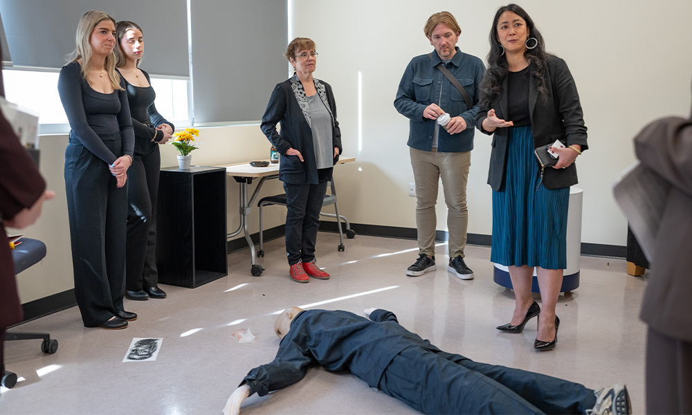 People gather around a mannequin laying on the floor.