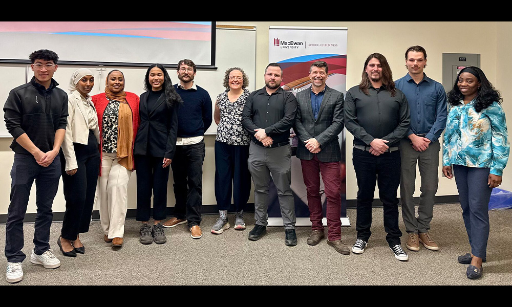 Several students stand in a lineup beside a MacEwan Ventures banner.