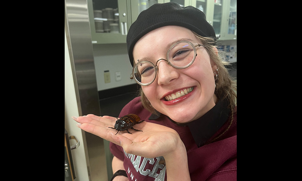 Kyana holds a giant cockrock and smiles at the camera