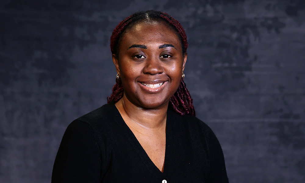 A woman wearing a black sweater smiles to the camera