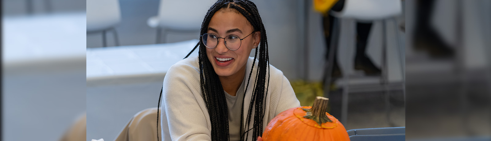 A student holds an orange pumpkin