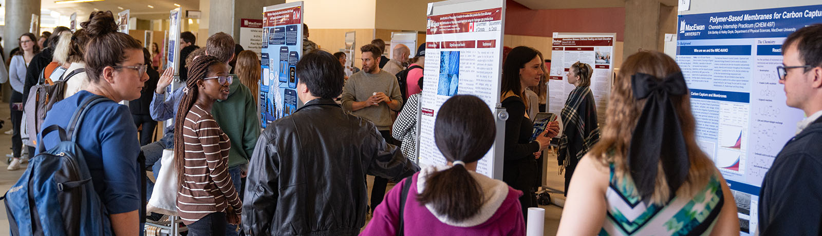 Students gather in front of posters at Student Research Day