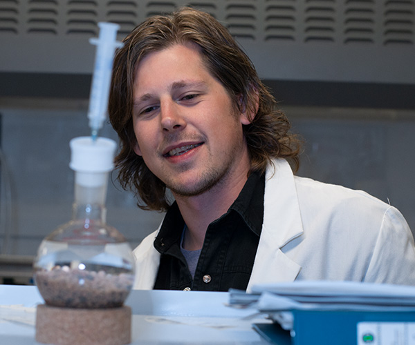 Student in Lab looking at beaker