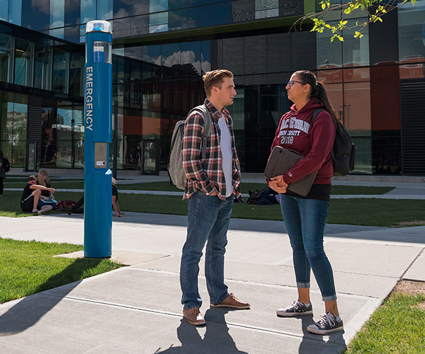 students standing outside talking around blue phone