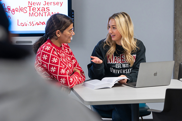 two students studying with laptop and book