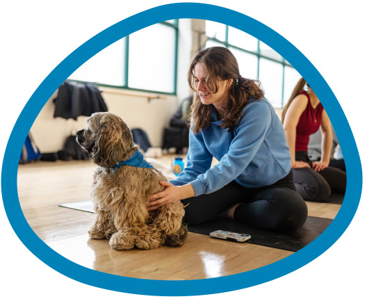 female student petting a dog in a yoga class