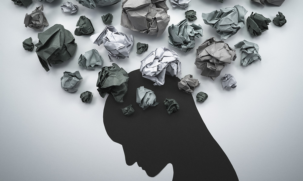 Illustration of a human head in profile with crumpled balls of paper overlaid on top of it