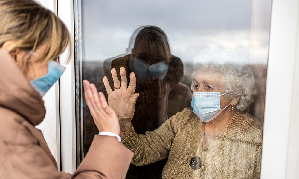 Image of two women greeting each other through a window