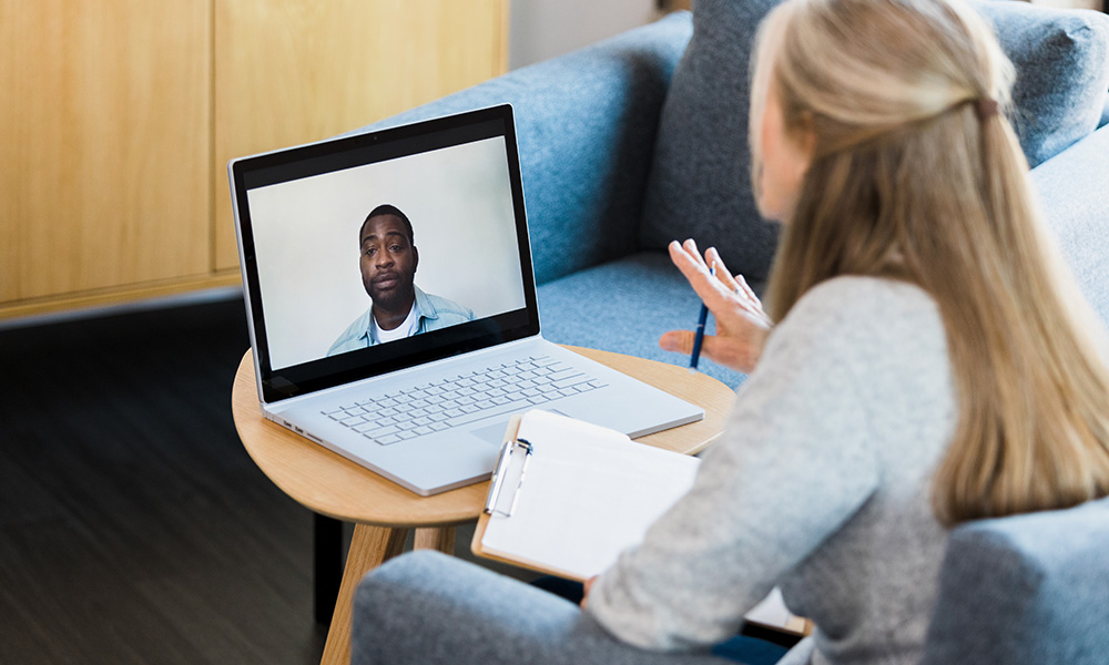 A service provider video chats on a laptop with a client  