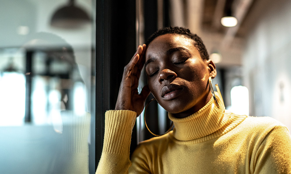 A woman leans against her hand with her eyes closed