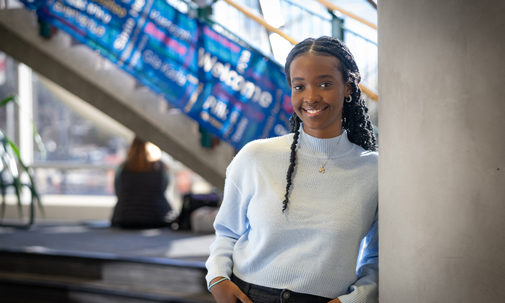 Emilie Rubayita leaning against a concrete pillar smiling