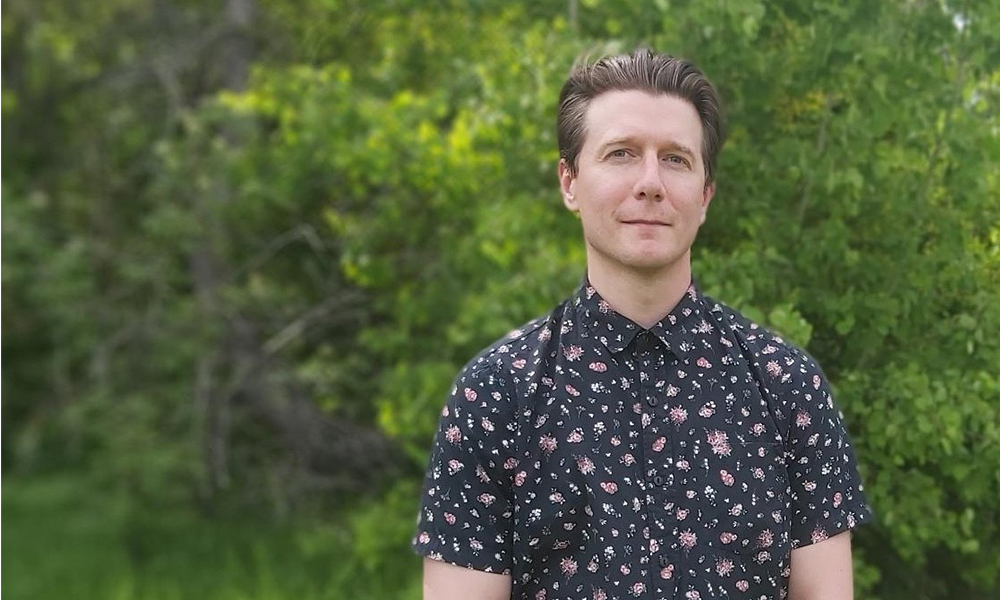 Brett McKay stands in front of a group of trees